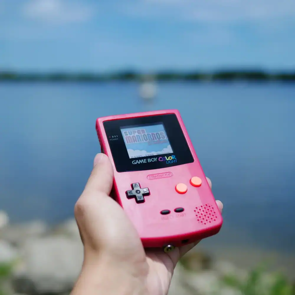 Custom pink Game Boy Color handheld gaming console outdoors.