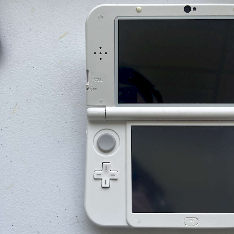 White Nintendo 3DS XL handheld gaming console on a white surface.