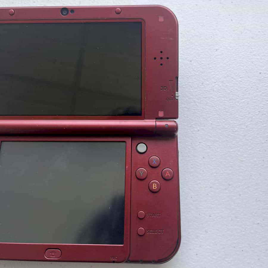 Red Nintendo 3DS XL handheld gaming console with dual screens and control buttons.