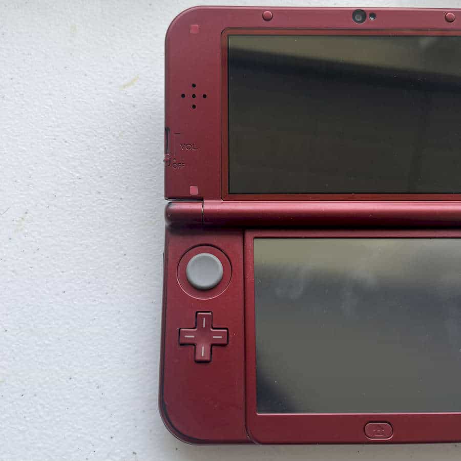 Red Nintendo 3DS XL handheld gaming console with dual screens and control buttons.