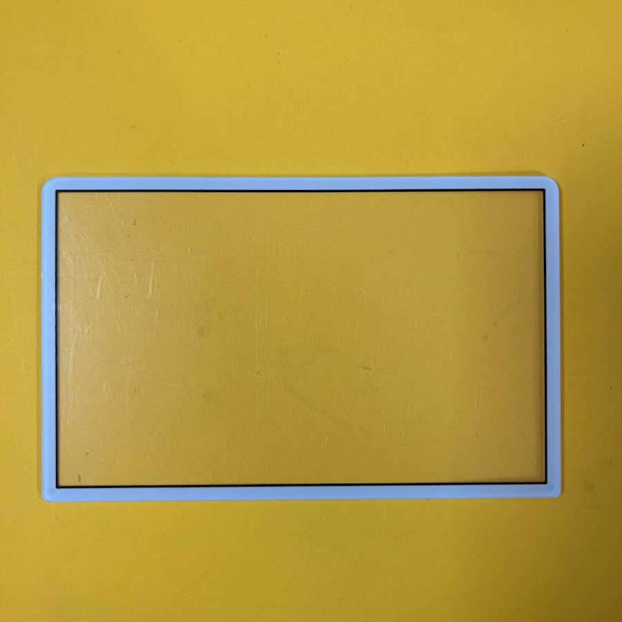 Black plastic top screen protector frame for Nintendo 3DS XL on yellow background.