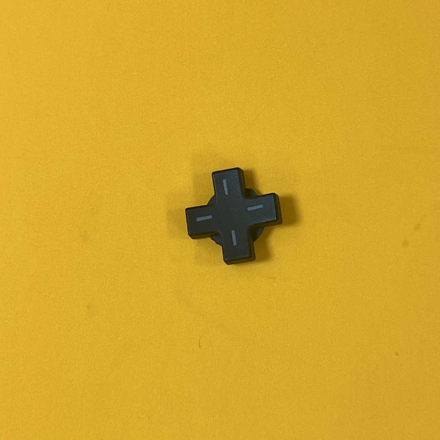 Black D-Pad replacement part for Nintendo 3DS XL on yellow background.