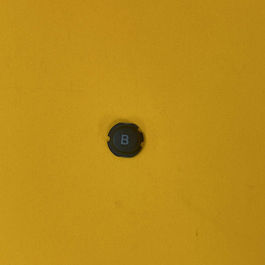 Black B button for Nintendo 3DS XL on yellow background.