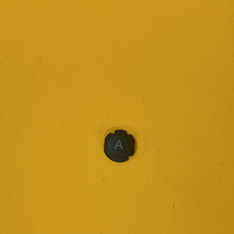 Black A button for Nintendo 3DS XL on yellow background.