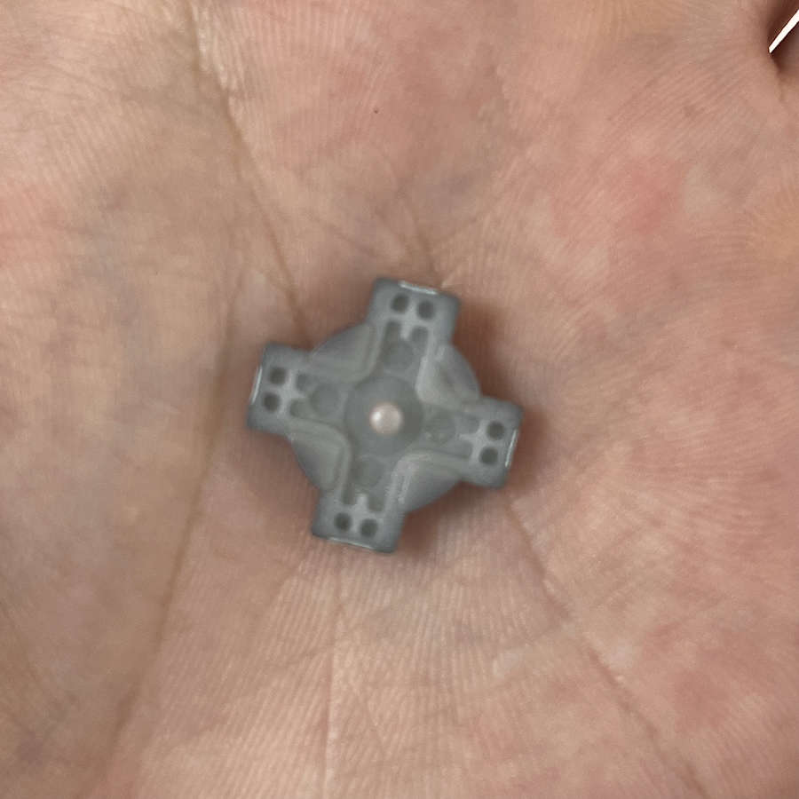 Turquoise D-Pad for Nintendo 3DS on a person's hand.