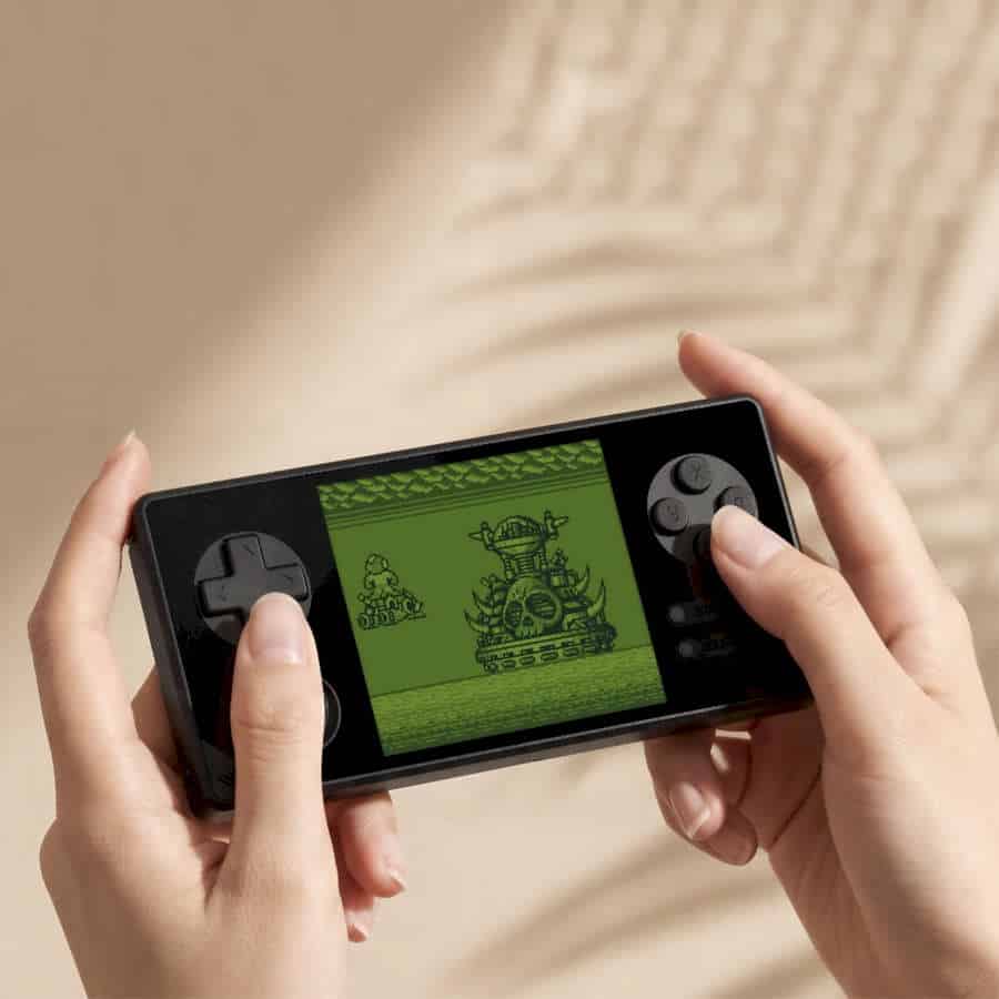 Person holding a handheld gaming device playing a retro game.